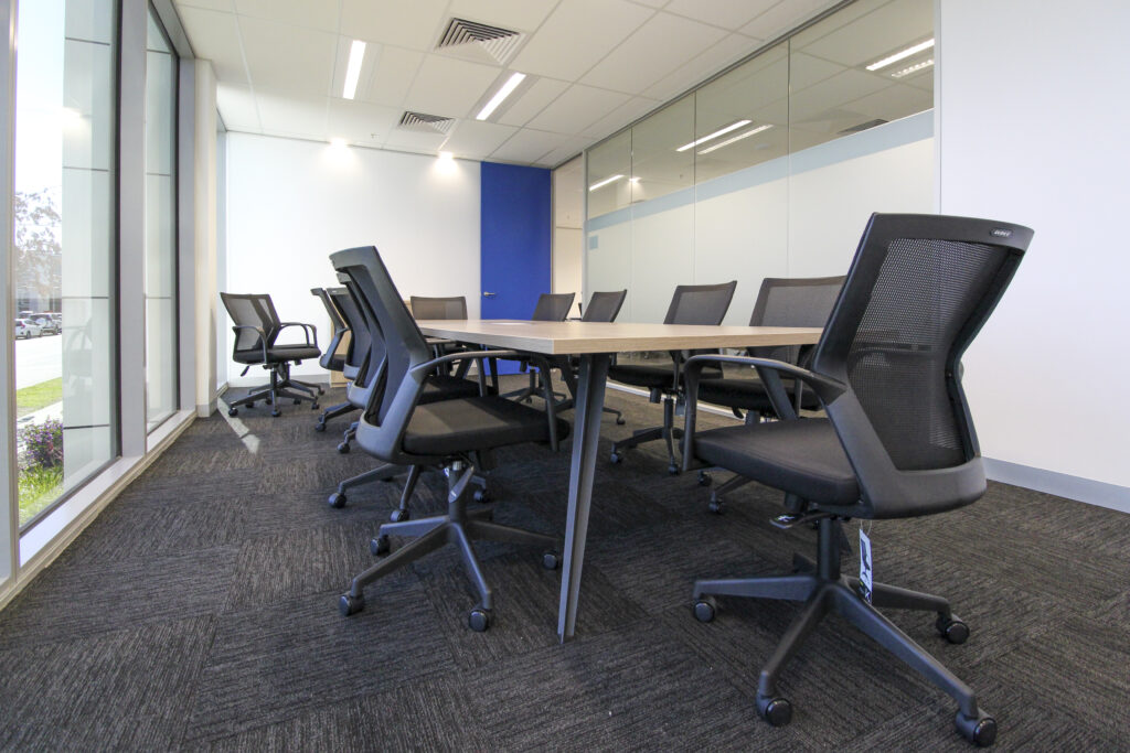 Modern conference room in Latrobe Health office featuring ergonomic chairs, glass partitioning, and a blend of neutral and blue design accents.